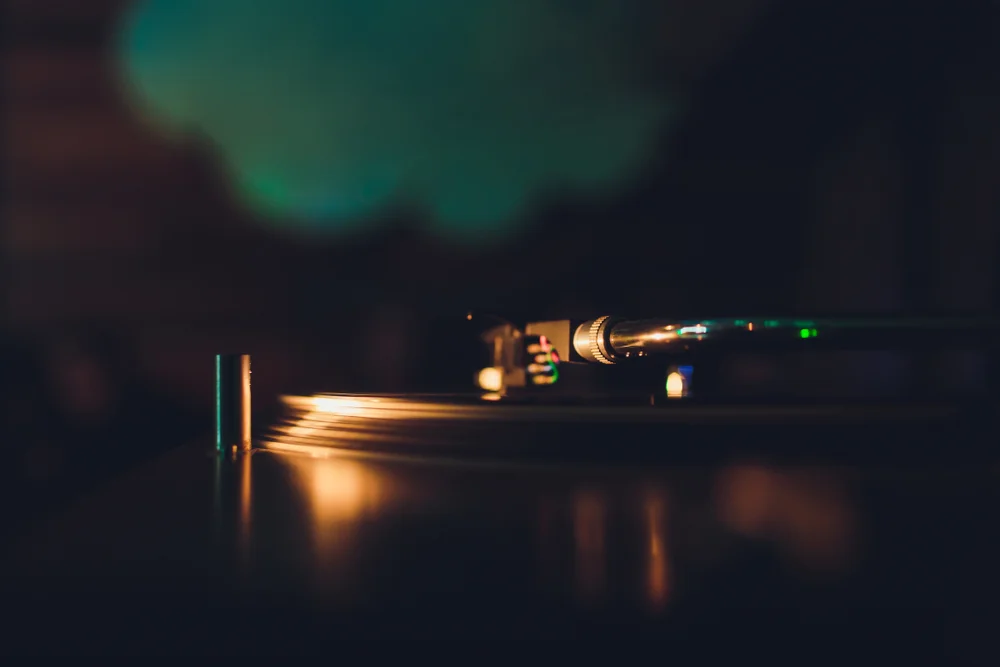 A turntable stylus resting on a vinyl record in low light