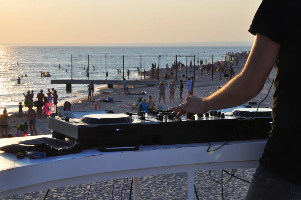 A DJ using a mixer above a beach in evening light