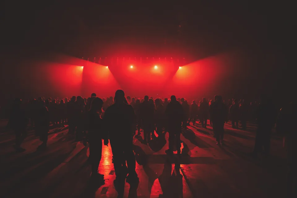 People gathered on a dance floor beneath red stage lights